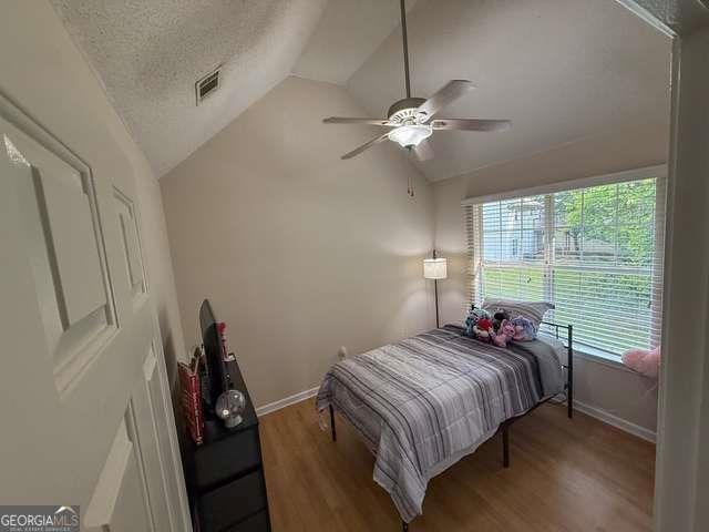 3269 N Winds Trl N, Douglasville, GA 30135 - bedroom featuring vaulted ceiling, baseboards, wood finished floors, a textured ceiling, and a ceiling fan