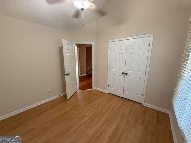 3269 N Winds Trl N, Douglasville, GA 30135 - unfurnished bedroom featuring light wood-style flooring, baseboards, ceiling fan, and a closet