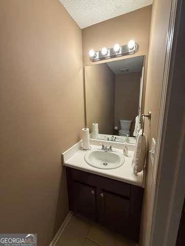 3269 N Winds Trl N, Douglasville, GA 30135 - half bath with vanity, a textured ceiling, tile patterned floors, and toilet