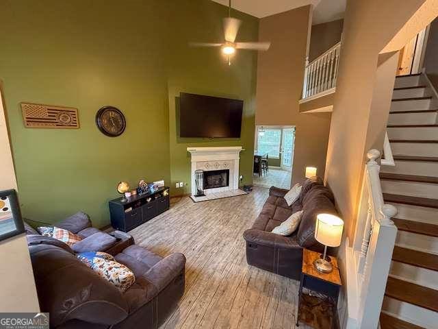 3269 N Winds Trl N, Douglasville, GA 30135 - living area with ceiling fan, a towering ceiling, stairs, wood finished floors, and a fireplace
