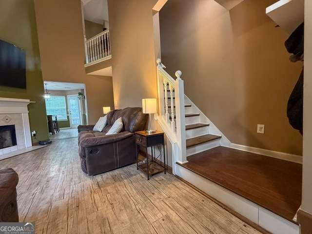 3269 N Winds Trl N, Douglasville, GA 30135 - living area featuring wood-type flooring, a towering ceiling, stairway, a premium fireplace, and baseboards