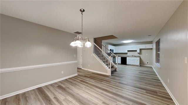 unfurnished dining area with sink, light wood-type flooring, and a notable chandelier