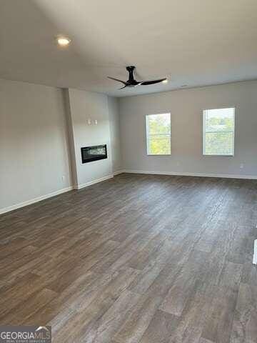 unfurnished living room featuring dark hardwood / wood-style floors, a healthy amount of sunlight, and ceiling fan