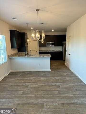 kitchen featuring kitchen peninsula, appliances with stainless steel finishes, dark wood-type flooring, and sink