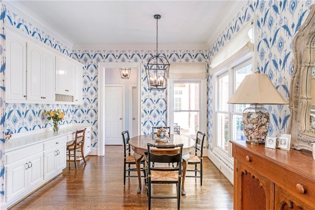 dining room featuring crown molding, an inviting chandelier, wood finished floors, and wallpapered walls