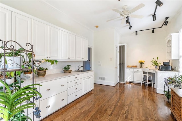 kitchen with crown molding, tasteful backsplash, visible vents, a sink, and wood finished floors