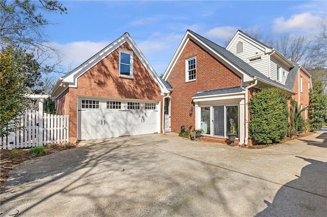 exterior space featuring a garage, concrete driveway, brick siding, and fence