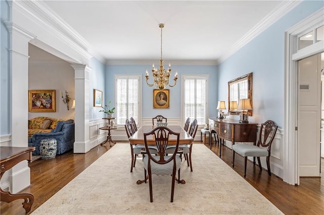 dining room with decorative columns, a chandelier, dark wood finished floors, and ornamental molding