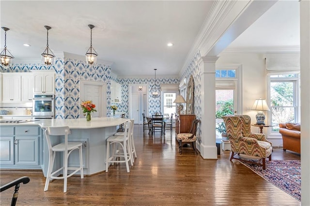 kitchen with wallpapered walls, dark wood-style flooring, oven, light countertops, and crown molding