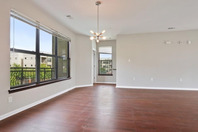 unfurnished room with dark hardwood / wood-style floors and an inviting chandelier