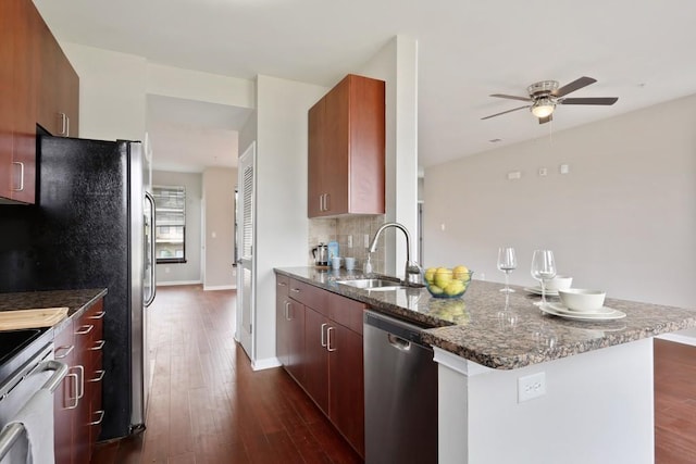 kitchen with stainless steel appliances, dark hardwood / wood-style floors, sink, and dark stone counters