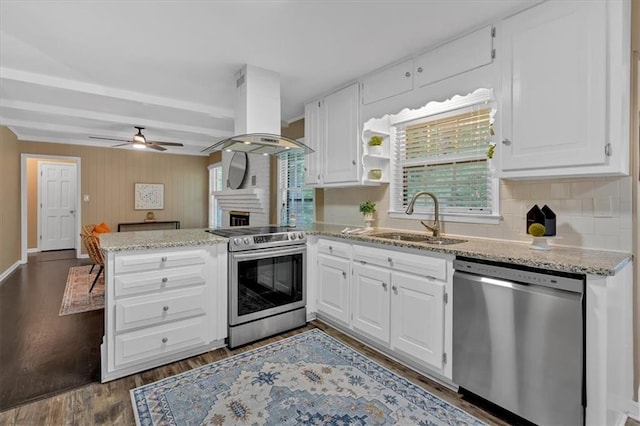 kitchen with kitchen peninsula, stainless steel appliances, sink, exhaust hood, and white cabinetry