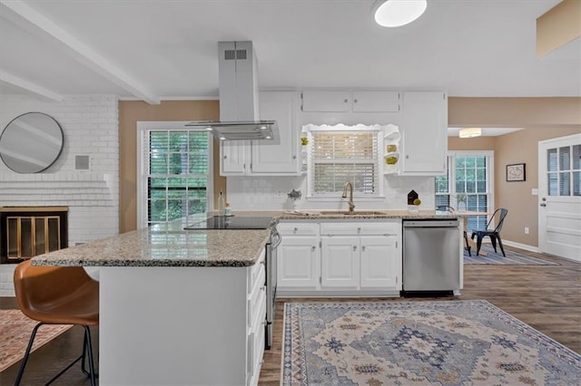 kitchen featuring sink, appliances with stainless steel finishes, island range hood, white cabinets, and hardwood / wood-style flooring