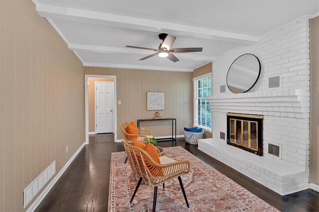 living room featuring ceiling fan, beam ceiling, dark hardwood / wood-style floors, and a fireplace