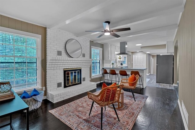 living room featuring beam ceiling, a fireplace, ceiling fan, and dark hardwood / wood-style flooring