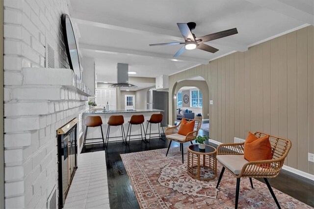 interior space with a fireplace, beam ceiling, ceiling fan, and dark wood-type flooring