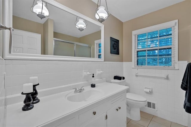 bathroom featuring tile patterned flooring, an enclosed shower, toilet, vanity, and tile walls