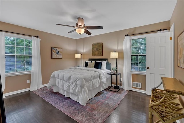 bedroom featuring ceiling fan, dark wood-type flooring, and multiple windows