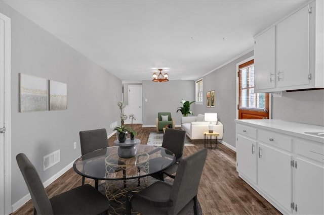 dining area featuring a notable chandelier, dark hardwood / wood-style floors, and crown molding