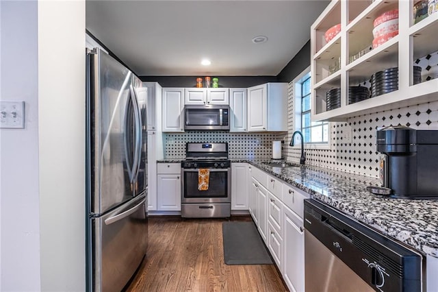 kitchen featuring dark hardwood / wood-style flooring, stainless steel appliances, sink, dark stone countertops, and white cabinetry