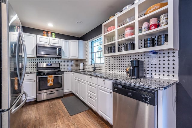 kitchen featuring sink, stainless steel appliances, dark hardwood / wood-style floors, dark stone countertops, and white cabinets