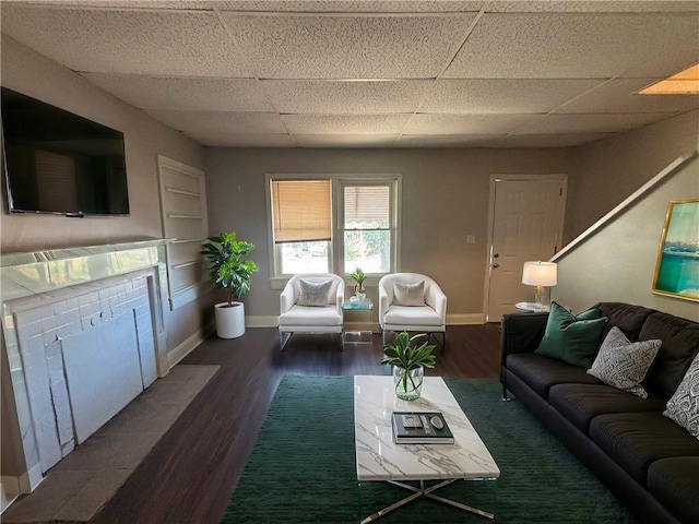 living room featuring dark wood-type flooring and a paneled ceiling