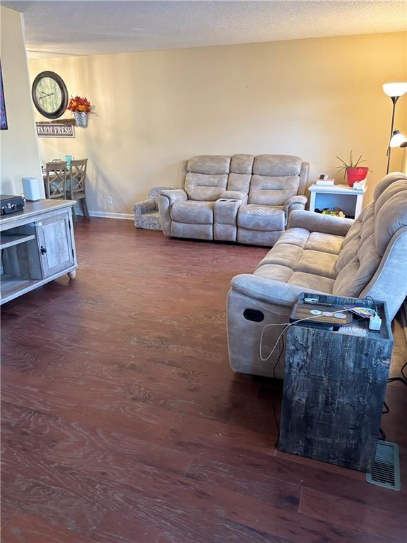 living area with a textured ceiling, baseboards, and wood finished floors