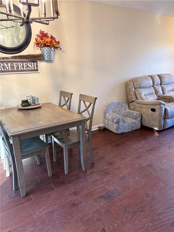 dining space with baseboards, wood finished floors, and an inviting chandelier