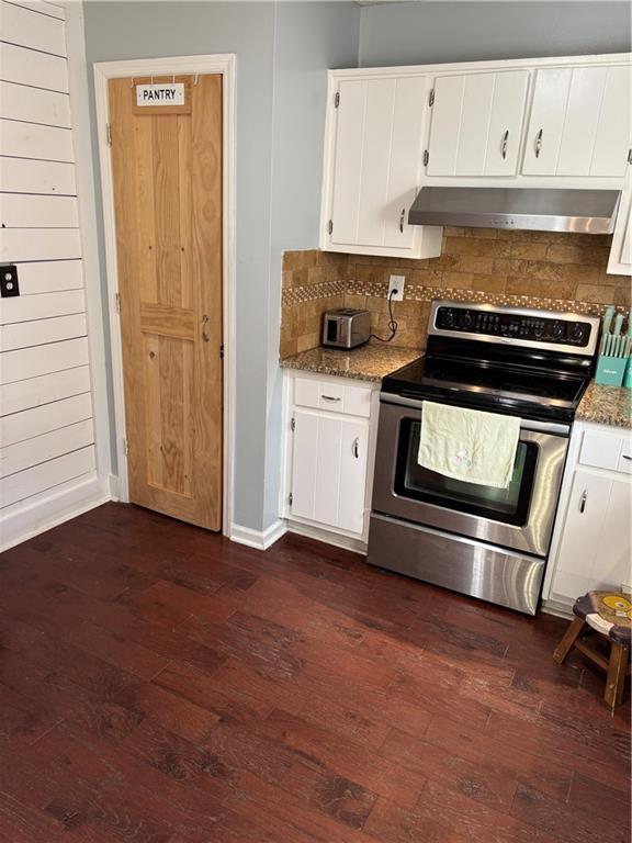 kitchen featuring dark wood finished floors, backsplash, white cabinets, stainless steel range with electric stovetop, and under cabinet range hood