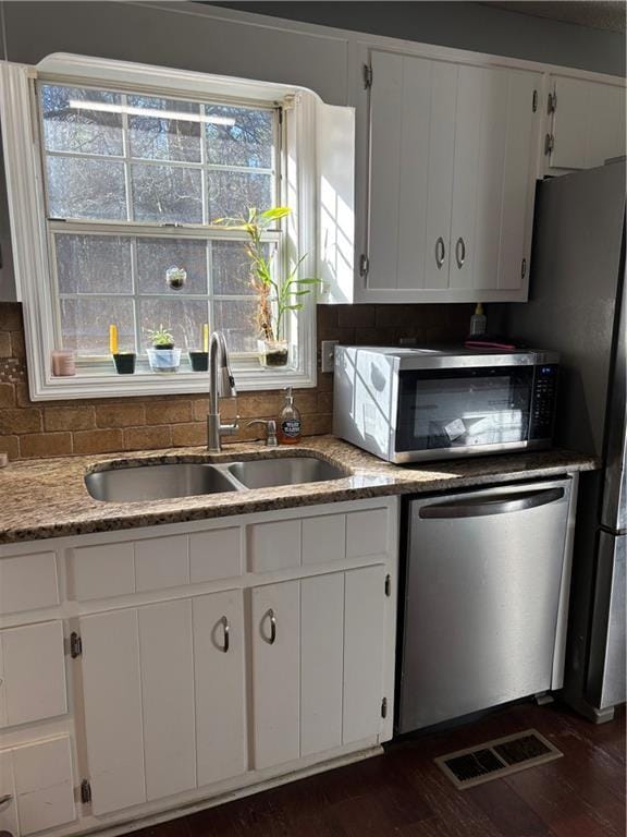 kitchen with stainless steel appliances, white cabinets, visible vents, and a sink