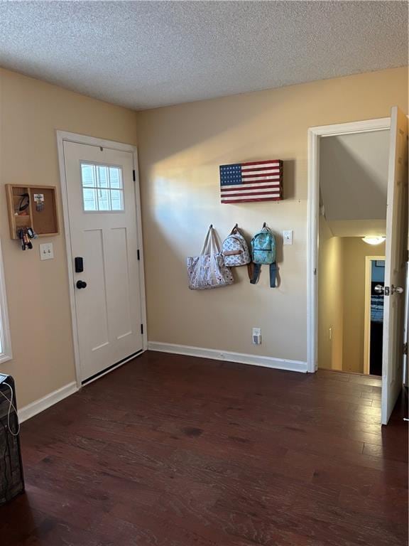 entryway featuring a textured ceiling, wood finished floors, and baseboards