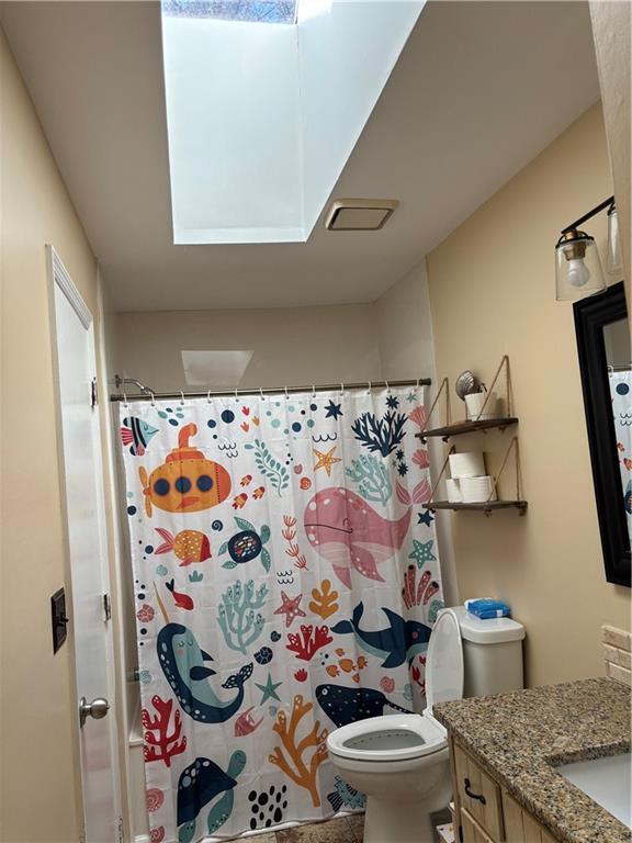 full bathroom with toilet, a skylight, a shower with curtain, and vanity