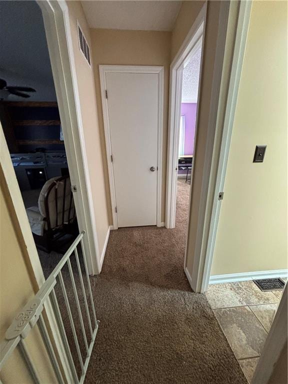 hallway featuring carpet flooring, visible vents, and baseboards