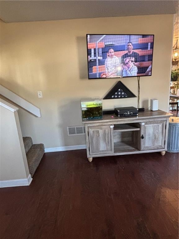 unfurnished living room with visible vents, dark wood finished floors, baseboards, and stairs