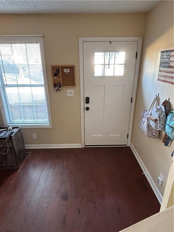 entryway with dark wood-style flooring, a textured ceiling, and baseboards