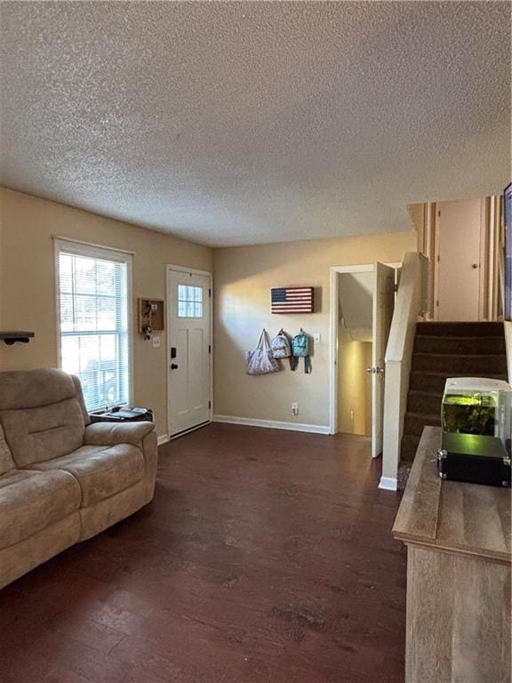 living room with stairs, baseboards, dark wood finished floors, and a textured ceiling