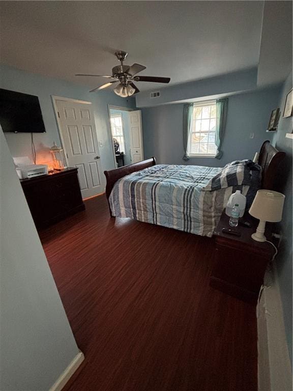 bedroom with visible vents, wood finished floors, a ceiling fan, and baseboards