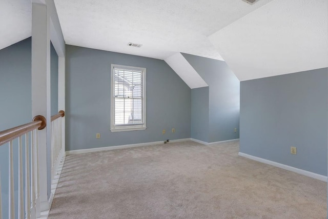 bonus room featuring a textured ceiling, vaulted ceiling, and light colored carpet