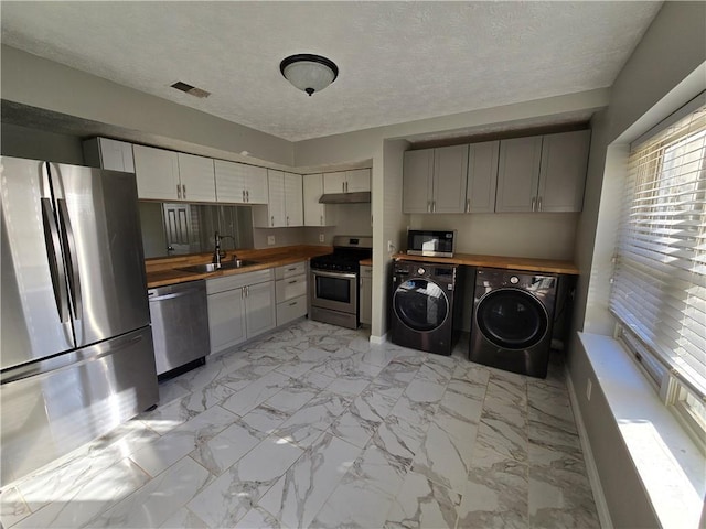 kitchen with stainless steel appliances, a sink, visible vents, marble finish floor, and independent washer and dryer