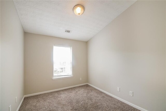 carpeted empty room with a textured ceiling, visible vents, and baseboards