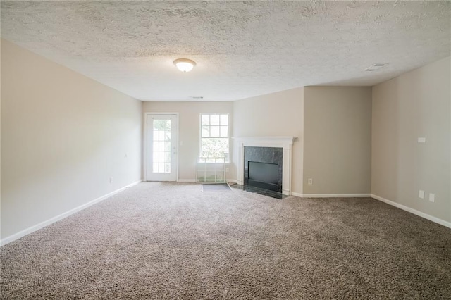 unfurnished living room featuring a textured ceiling, carpet floors, a premium fireplace, and baseboards