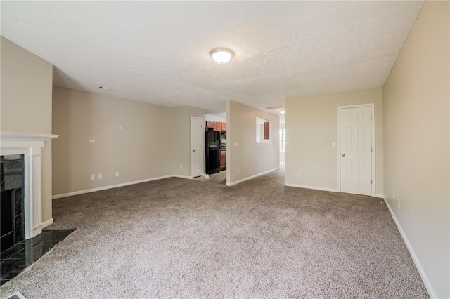 unfurnished living room featuring carpet floors, a fireplace, a textured ceiling, and baseboards