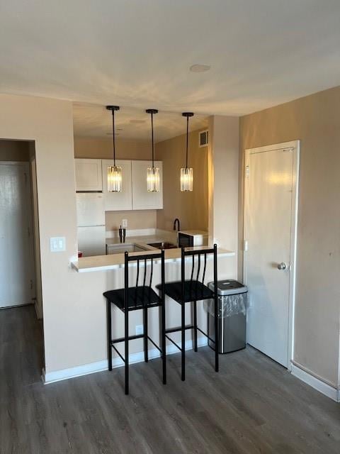 kitchen with sink, white cabinetry, a kitchen breakfast bar, kitchen peninsula, and white fridge