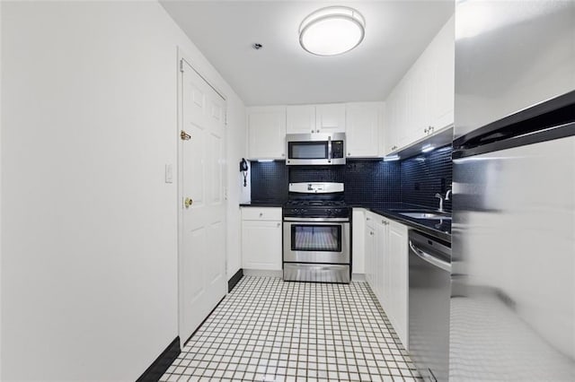 kitchen featuring dark countertops, tasteful backsplash, white cabinets, and stainless steel appliances