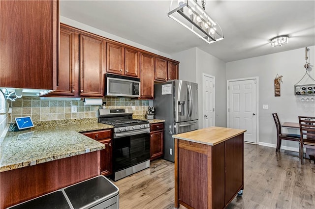 kitchen featuring appliances with stainless steel finishes, light wood-type flooring, backsplash, wooden counters, and a kitchen island