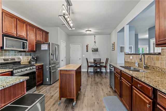 kitchen with stainless steel appliances, a sink, backsplash, and light wood-style flooring