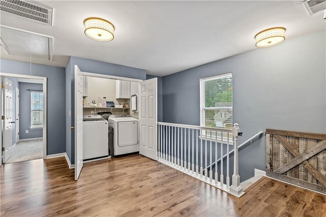 laundry room featuring attic access, washing machine and dryer, light wood-style flooring, and baseboards