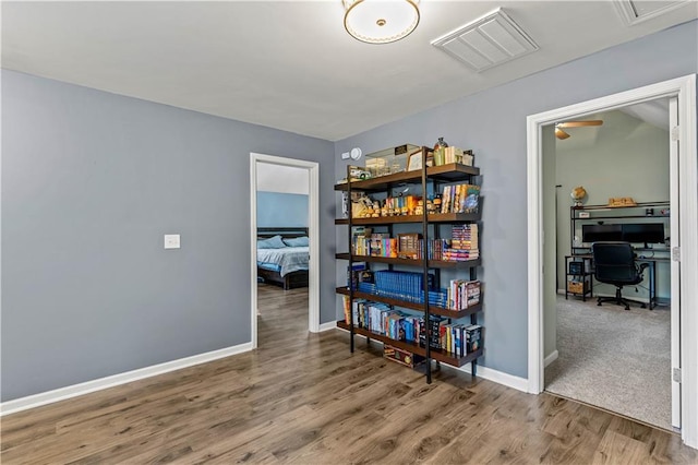 miscellaneous room featuring a desk, wood finished floors, and baseboards