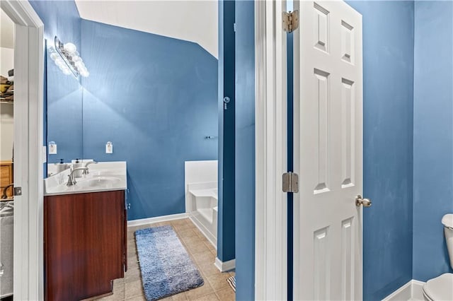 full bathroom with a garden tub, vanity, toilet, tile patterned floors, and baseboards