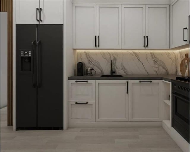 kitchen featuring black fridge, wall oven, sink, and white cabinets